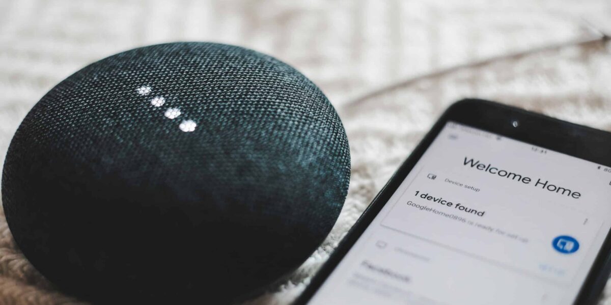 turned-on charcoal Google Home Mini and smartphone