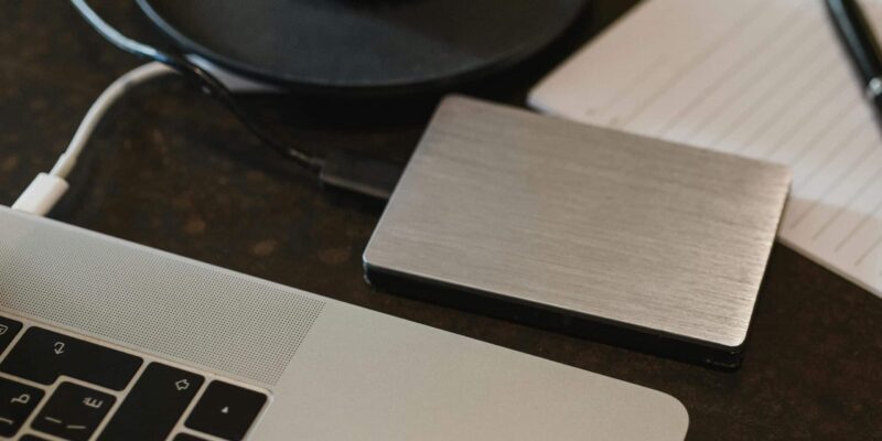 Free Closeup of an external hard drive connected to a laptop with a USB cable on a desk. Stock Photo