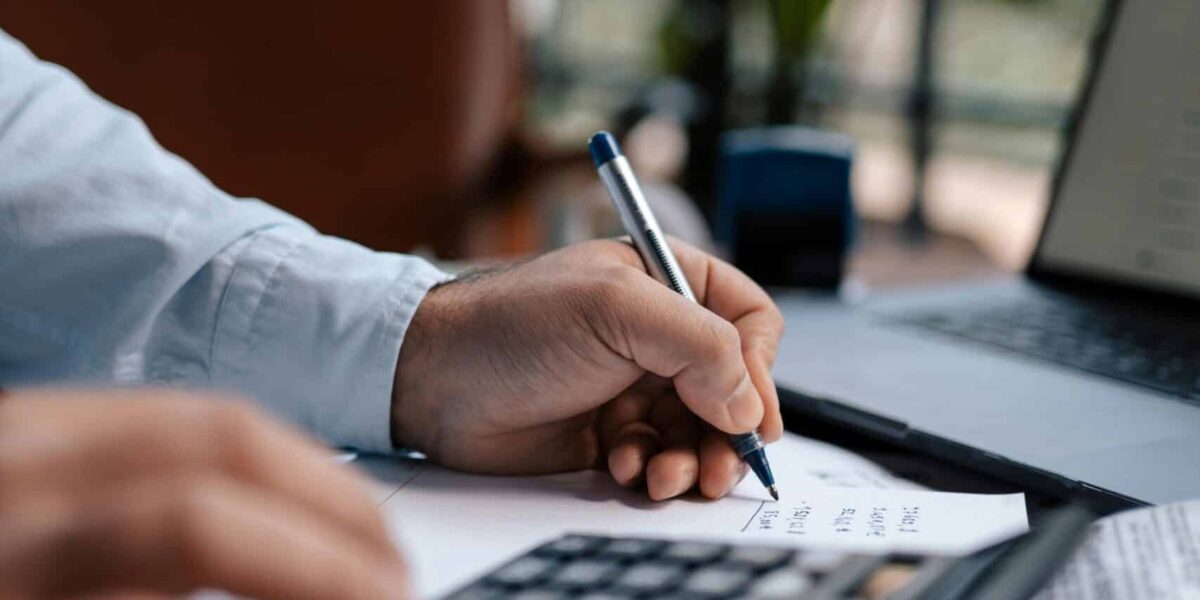 Free A person calculating finances with a calculator and pen on a desk indoors. Stock Photo