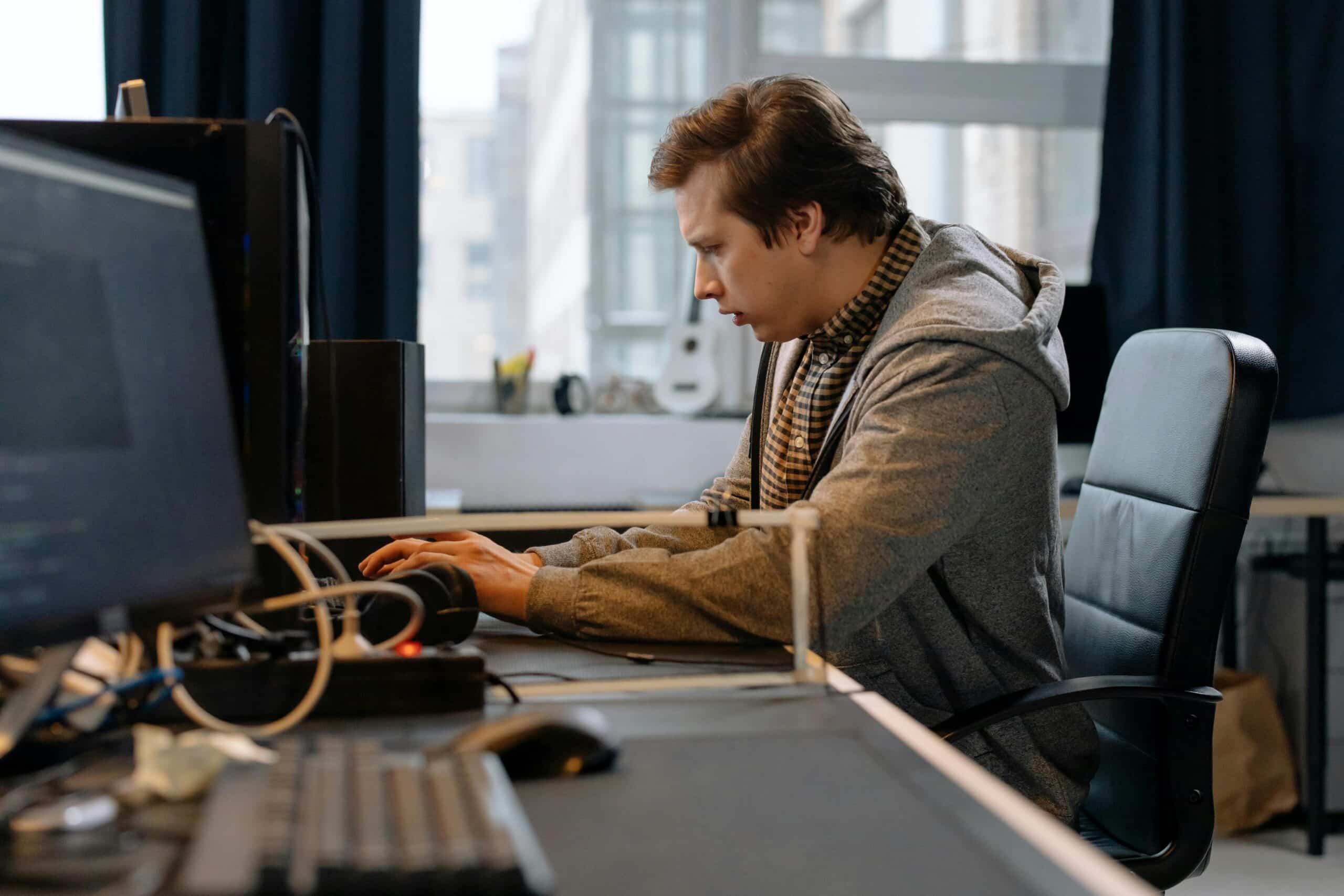 Free A concentrated professional working at a computer in a modern office setting. Stock Photo