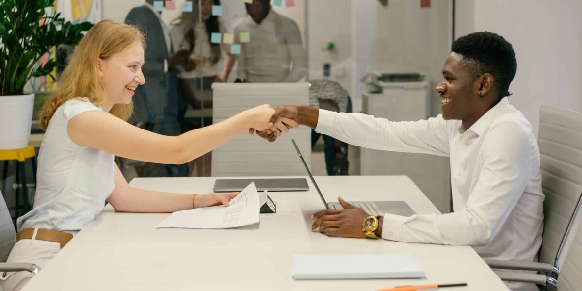 Free Business professionals completing a successful deal with a handshake in a modern office setting. Stock Photo